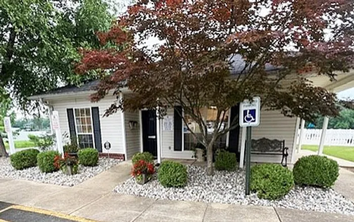 Charming suburban home with a beautifully landscaped entrance, featuring lush greenery and a welcoming bench.
