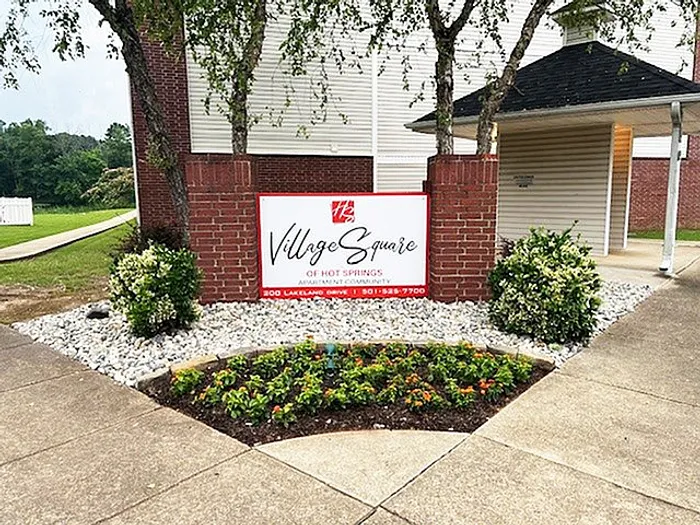 Inviting entrance to Village Square, Hot Springs, featuring a well-maintained landscaped garden and a welcoming sign.
