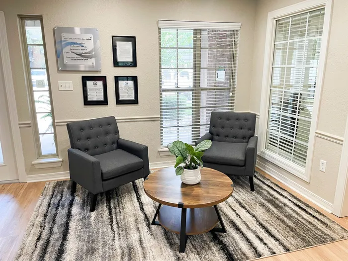 Inviting living room with modern gray armchairs, a stylish wooden coffee table, and natural light streaming through large windows.