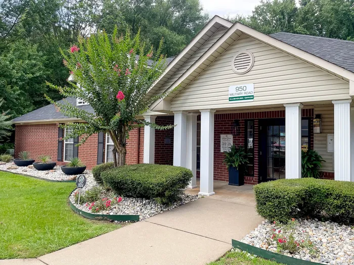 Charming clubhouse with inviting entrance, lush landscaping, and vibrant greenery at 950 Military Road.