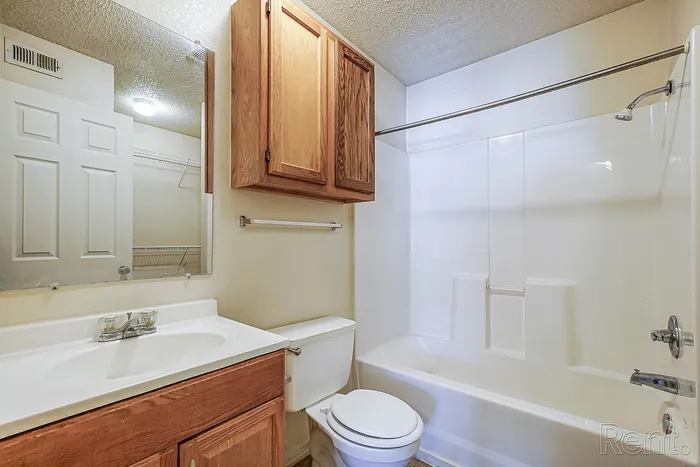 Modern bathroom featuring sleek cabinetry, pristine white bathtub, and ample mirror space.