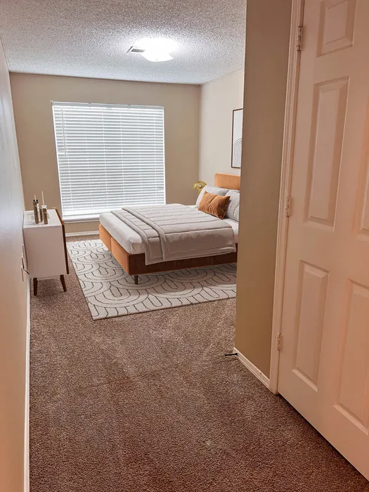 Inviting bedroom featuring a plush bed, cozy carpet, and abundant natural light from large windows.