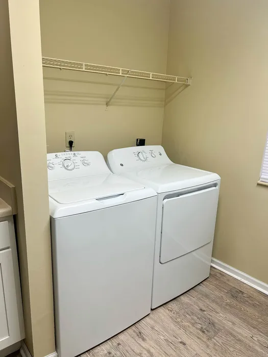 Pristine laundry room featuring modern washer and dryer under stylish open shelving, offering efficient laundry solutions.