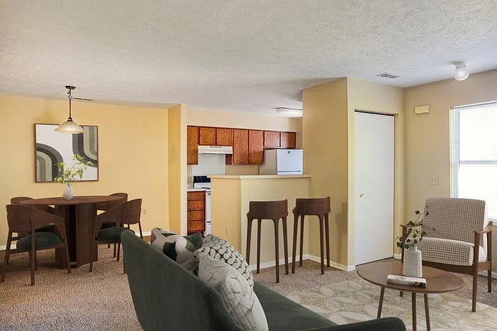 Charming open-plan living and dining area with modern furnishings, cozy carpet, and a welcoming kitchen view.