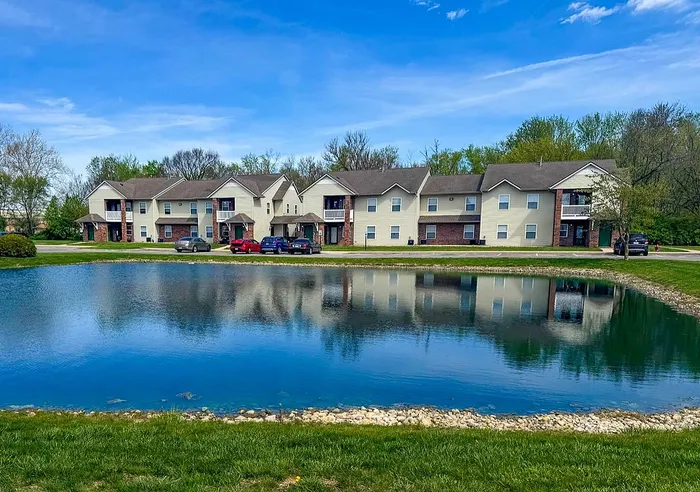 Charming apartment complex with serene pond and lush greenery, offering a peaceful living environment.