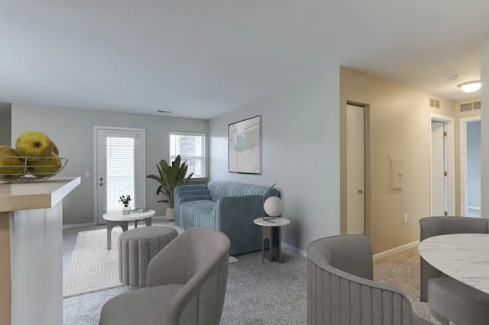 Bright and inviting modern living area featuring a cozy blue sofa, elegant gray chairs, and a chic round table.