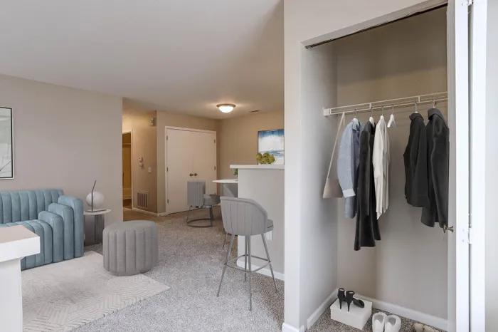 Chic and cozy apartment living area with modern blue sofa, stylish bar stools, and a spacious open closet. Perfect blend of comfort and elegance.