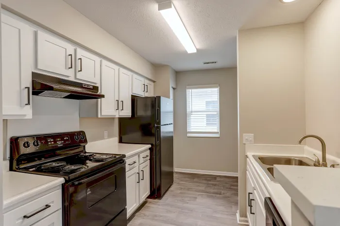 Contemporary kitchen with sleek black appliances, elegant white cabinetry, and clean countertops, offering a bright and inviting cooking space.