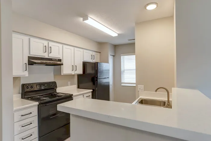 Modern kitchen featuring sleek white cabinets, a black appliance suite, and a bright, welcoming ambiance.
