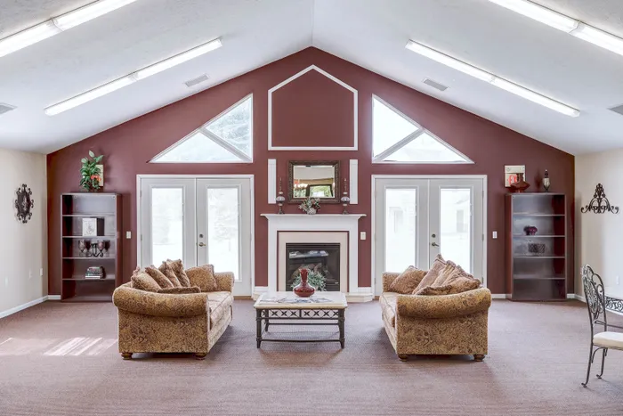 Inviting living room featuring plush sofas, a charming fireplace, and elegant double doors with abundant natural light.