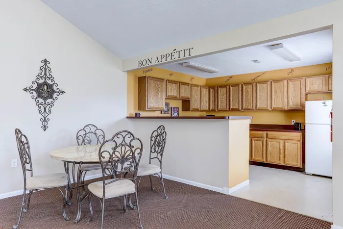 Charming dining area with a round table and ornate chairs, leading to a cozy kitchen adorned with wooden cabinets and inviting decor.