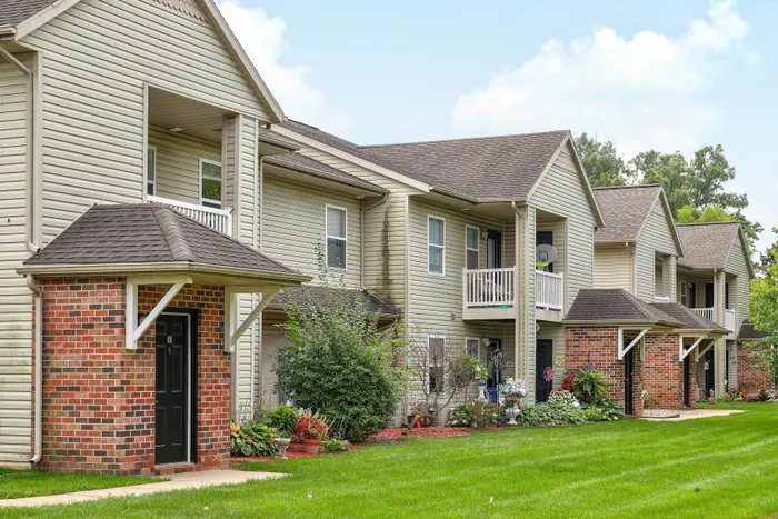 Charming and inviting multi-unit residential complex with brick accents and lush green landscaping, perfect for a serene living experience.
