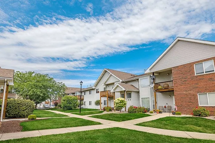 Charming apartment complex with well-maintained landscaping and modern architecture under a picturesque blue sky.