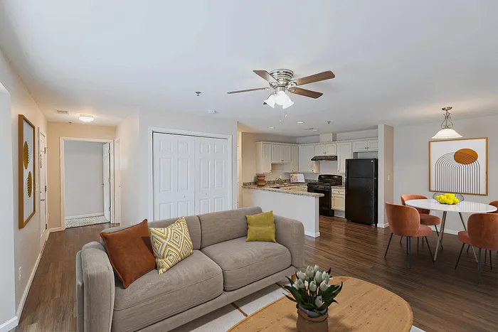 Modern open-concept living space with a cozy beige sofa, stylish dining area, and sleek kitchen featuring white cabinetry and dark appliances.