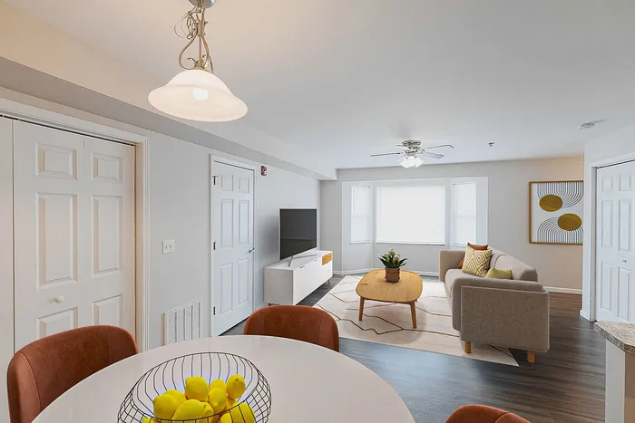 Bright, modern living room with a cozy sofa, sleek TV stand, and elegant dining area, complemented by natural light and stylish decor.