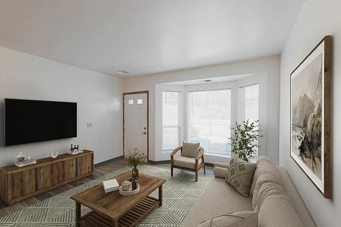 Inviting living room with natural light, featuring a cozy beige sofa, modern decor, and large windows overlooking serene outdoor views.