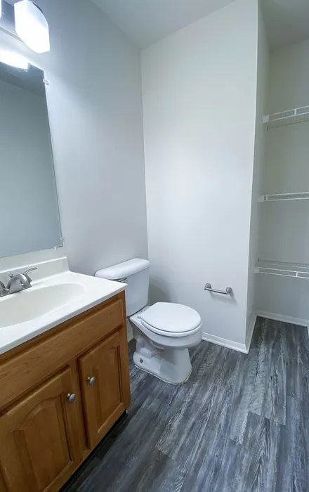 Modern bathroom with sleek design, featuring elegant wooden cabinetry, a pristine white countertop, and stylish gray flooring.