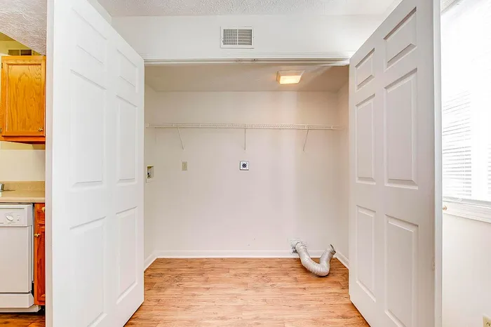 Bright laundry nook with sleek sliding doors and warm wood flooring, ready for convenient washer and dryer setup.