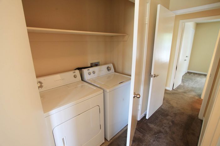 Convenient in-unit laundry area featuring a modern washer and dryer set with built-in shelving for easy organization.