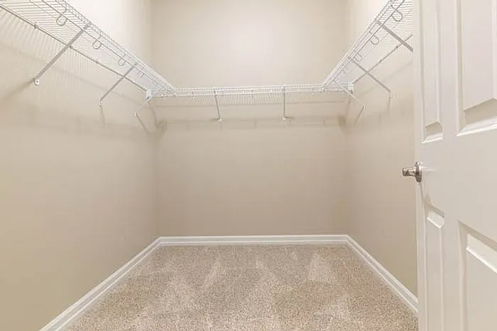 Spacious walk-in closet with sleek wire shelving and plush carpeting, perfect for organized living.