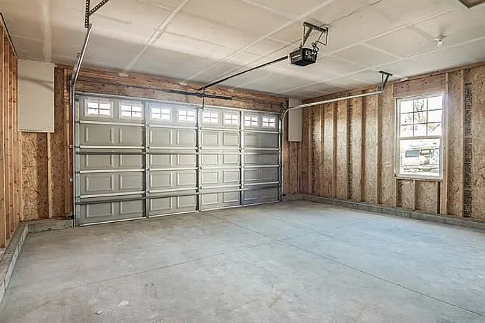 Spacious two-car garage with natural light and modern garage door, perfect for storage and convenience.