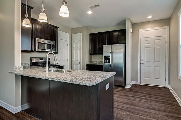 Modern kitchen with sleek granite countertops, stainless steel appliances, and stylish pendant lighting over a spacious island.
