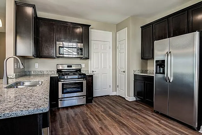 Modern kitchen featuring sleek dark cabinets, granite countertops, and stainless steel appliances, offering a touch of elegance and functionality.