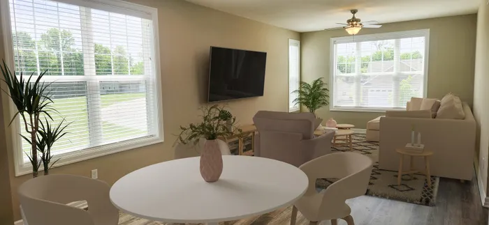 Bright and inviting living room with large windows, cozy seating, modern decor, and lush green plants, perfect for relaxing and entertaining.