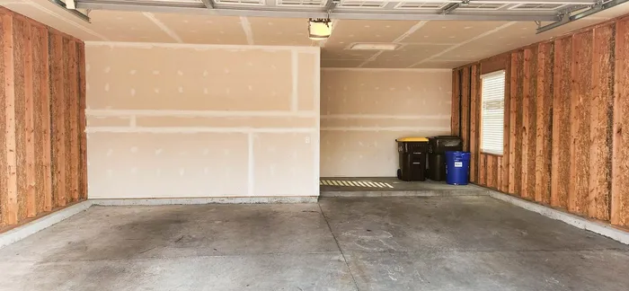 Spacious double garage with fresh drywall, natural wooden accents, and ample storage space.