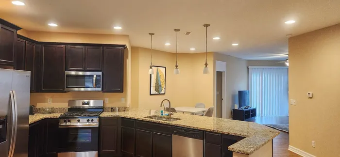 Elegant open-concept kitchen with granite countertops, modern appliances, and ambient lighting leading into a cozy living area.