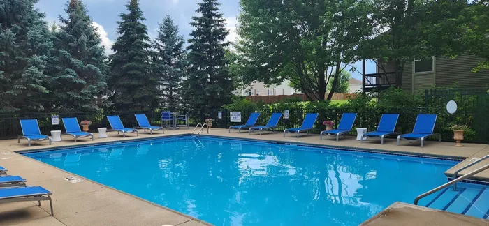 Inviting outdoor swimming pool surrounded by lush greenery and modern blue loungers.