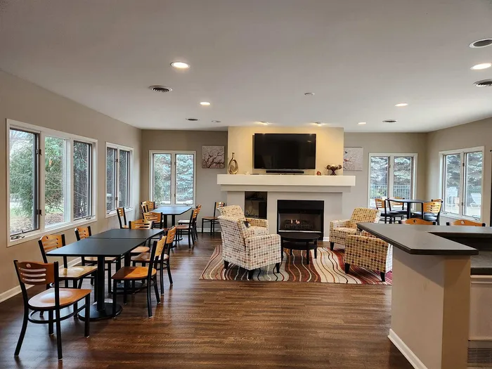 Inviting community lounge area with modern seating, cozy fireplace, and large windows offering lush garden views.