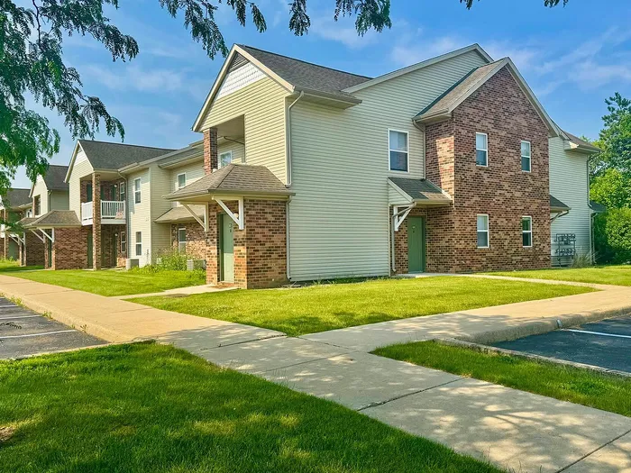 Charming residential building with brick façade and lush green lawns, perfect for a serene living environment.