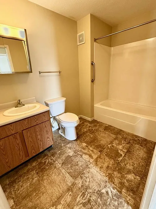 Elegant bathroom with stylish marble-patterned flooring, featuring a modern vanity, large mirror, and bathtub with overhead shower.