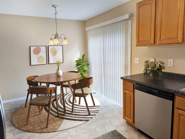 Inviting dining area with a modern wooden table set, chic decor, and natural light streaming through glass doors.