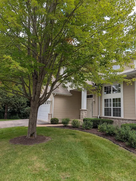 Charming exterior of a cozy home with lush greenery, large windows, and a welcoming entrance.