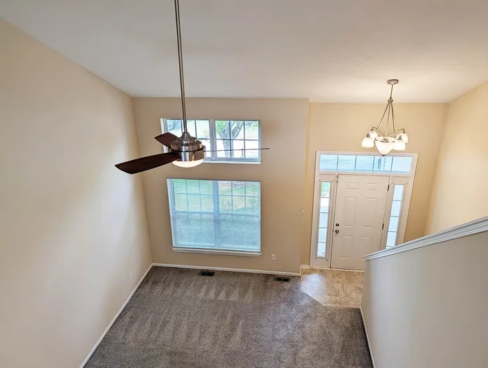 Bright and inviting apartment entryway with modern ceiling fan, large windows, and elegant lighting.