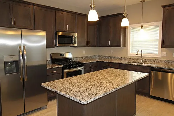 Modern kitchen with elegant granite countertops, stainless steel appliances, and rich wooden cabinetry.