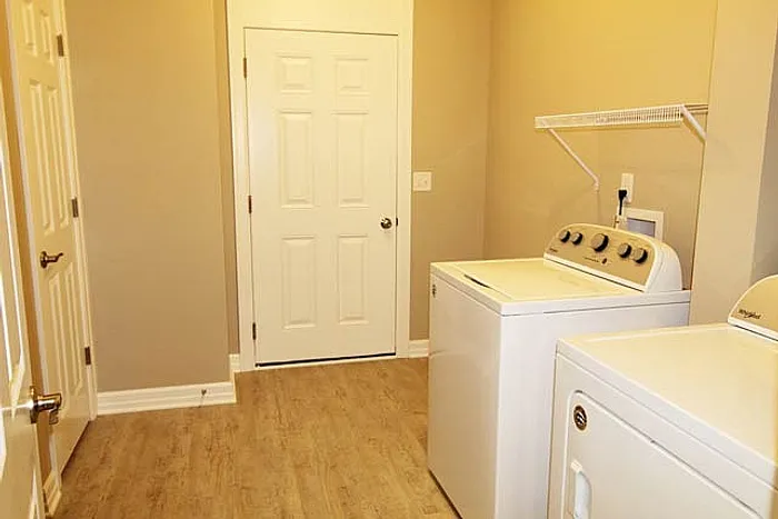 Chic laundry room with modern washer and dryer, featuring elegant wood flooring and ample storage space.