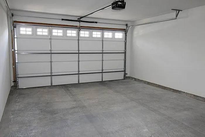 Spacious, well-lit garage with polished concrete floor and modern automatic door, perfect for secure vehicle storage.
