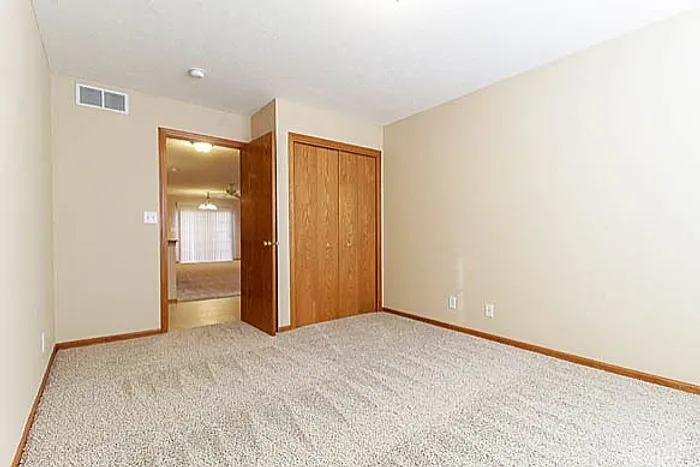 Bright and inviting empty room with plush carpet and warm wood trim, offering a spacious canvas for your dream home design.