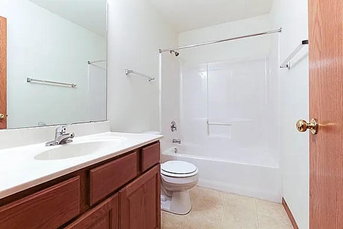 Bright and modern bathroom featuring a sleek white bathtub, elegant wooden cabinetry, and a spacious vanity.