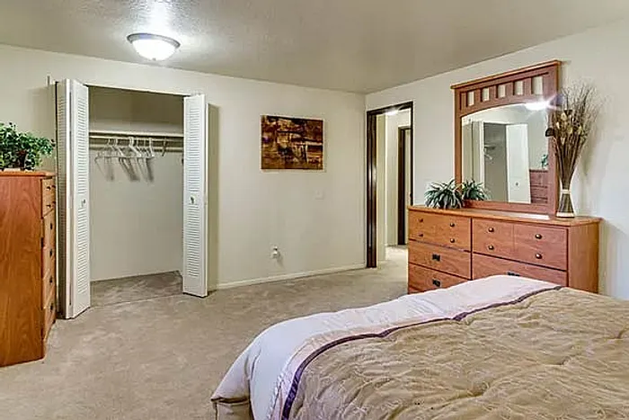 Inviting bedroom with plush carpeting, spacious walk-in closet, warm wooden furnishings, and elegant decor.