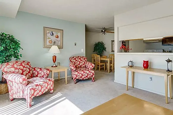 Inviting living room with vibrant floral armchairs, elegant decor, and a view into the cozy dining area.