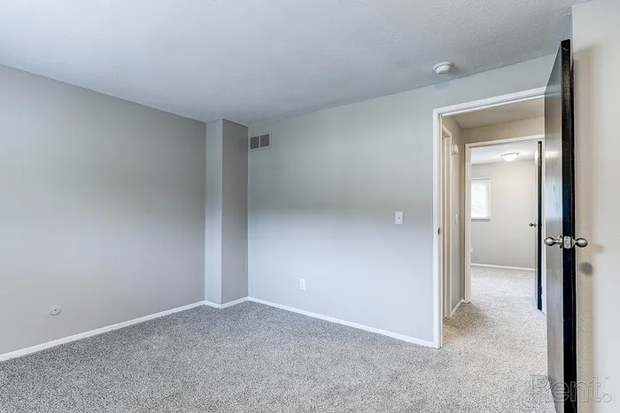 Bright and spacious bedroom with plush carpeting and a modern neutral color palette, perfect for personalization.