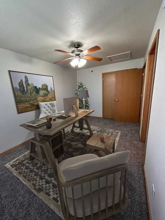 Chic home office with a modern wooden desk, elegant artwork, plush seating, and a ceiling fan, creating a cozy workspace.