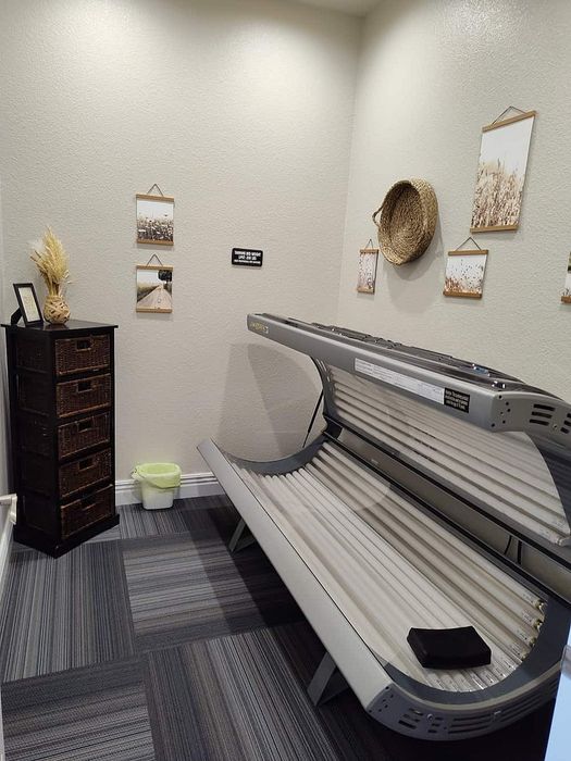 Inviting wellness oasis featuring a sleek tanning bed, wicker drawers, and serene wall art, perfect for relaxation.