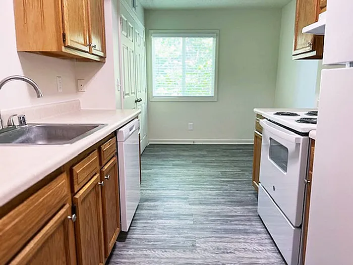 Bright galley kitchen with modern appliances, sleek countertops, and large window providing ample natural light.