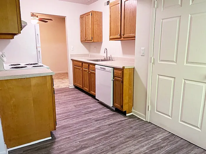 Cozy kitchen with modern wood cabinets, sleek countertops, and a new dishwasher, complemented by stylish laminate flooring.