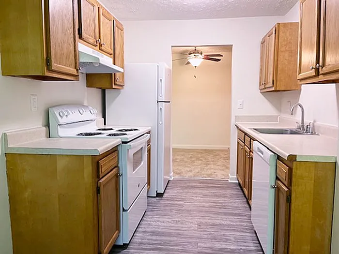 Bright and inviting kitchen with modern appliances, wooden cabinets, and a stylish laminate floor leading into a well-lit dining area.
